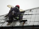 Skupina českolipských profesionálních hasičů přibíjí plechy na domě v Kamenickém Šenově